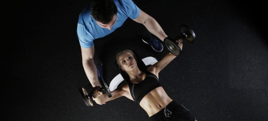 a man helping a woman lift weights 